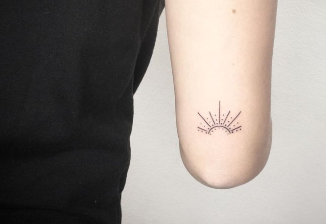 tatuaje sol naciente codo